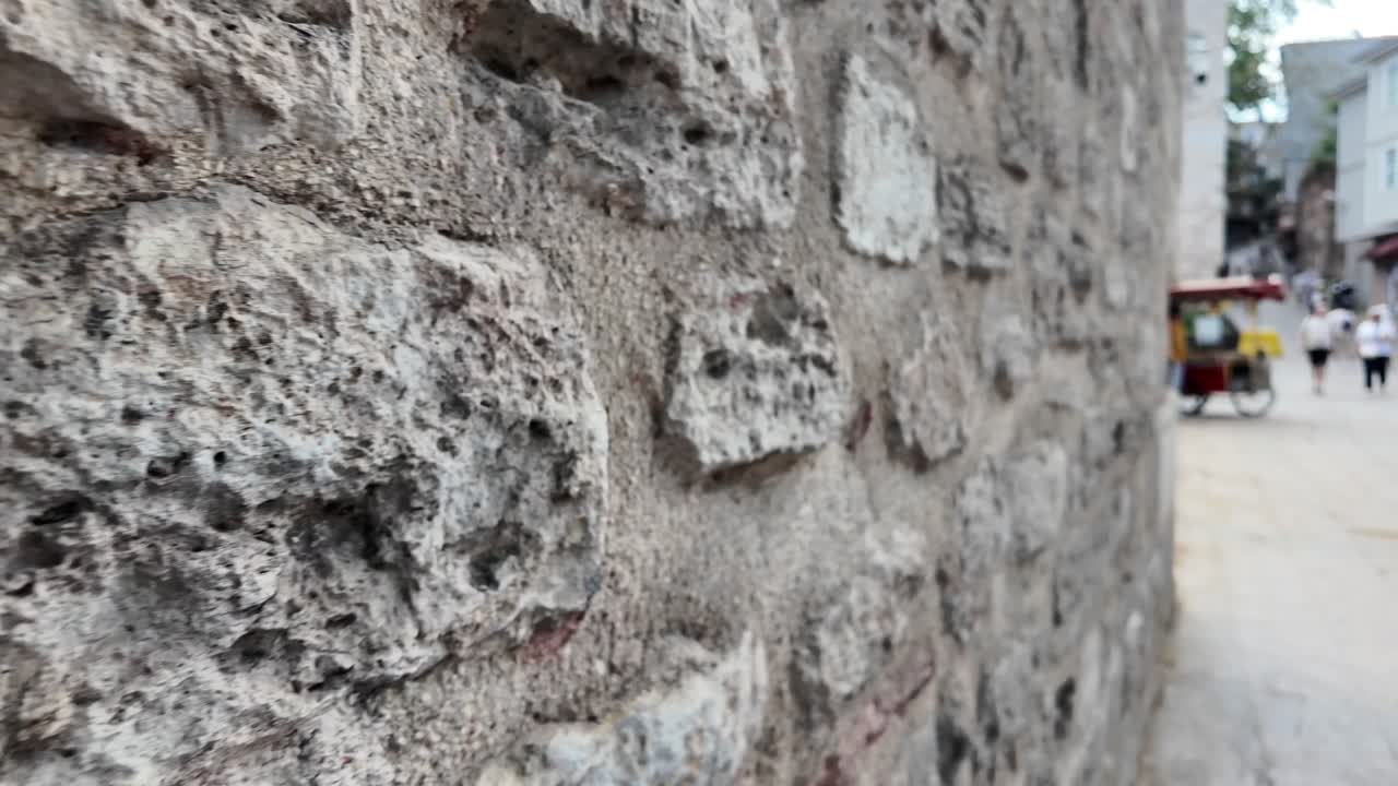 Close-up de uma parede de pedra antiga com fundo de rua desfocado