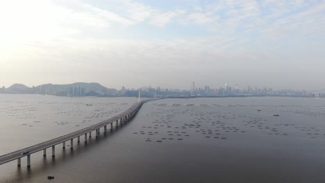 hong kong shenzhen bay bridge with tin shui wai buildings in the horizon and fish and oyster cultivation pools, aerial view