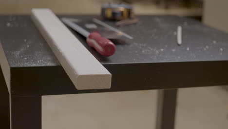 Slowmotion-shot-of-a-worker-placing-down-a-marked-piece-of-wood-and-his-tools-onto-his-workbench