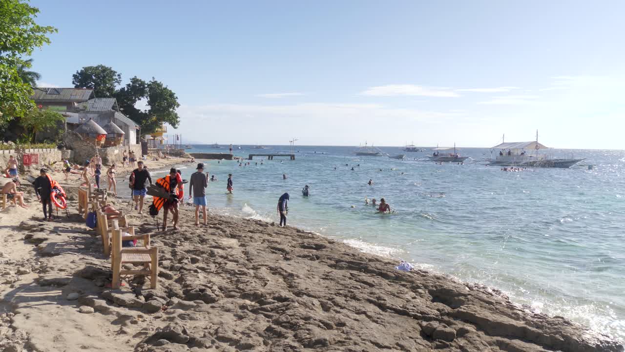People Enjoying Tropical Beach In Moalboal Town, Cebu Island In The Philippines. Static Shot
