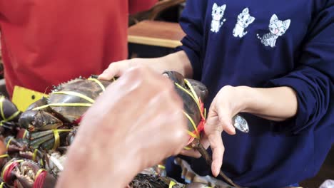 Buying-fresh-crab-in-Thailand-market,-handheld-view