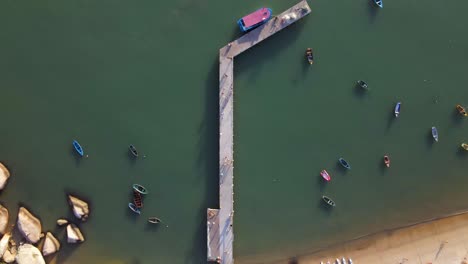 muelle de mar y botes pequeños anclados cerca de la playa, antena arriba hacia abajo
