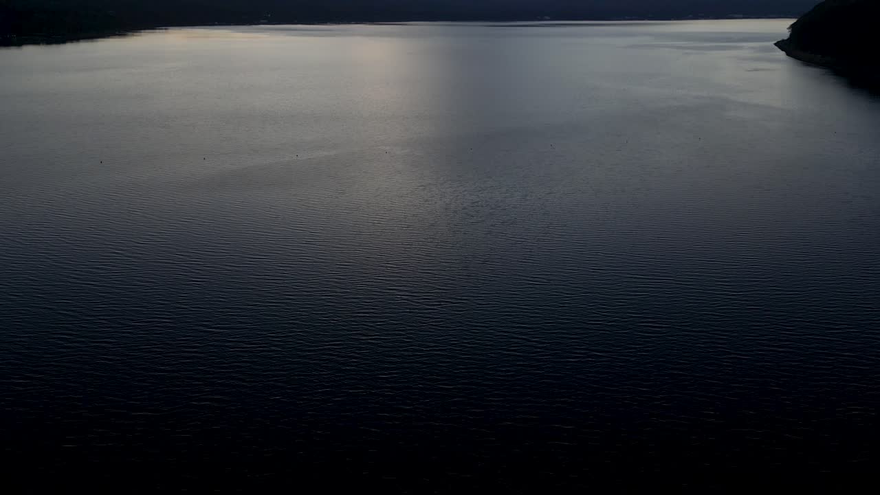 Slow motion cinematic drone tilt up over Mt. Fuji at sunset over lake