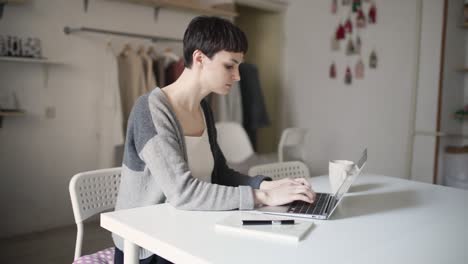 Junge-Frau-Tippt-Nachrichten-Per-Tastatur-Laptop-Am-Tisch-Im-Heimbüro