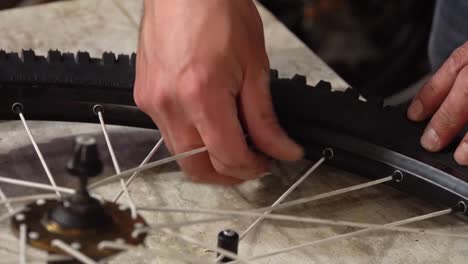 man's hand twists the nipple on a bicycle wheel