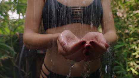 woman in shower catching water in hands showering outdoors in nature wearing bikini unrecognizable person