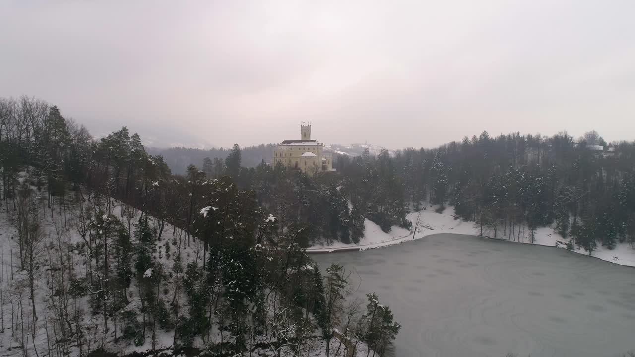 Vista aerea di un lago ghiacciato e di un castello da fiaba in lontananza in inverno