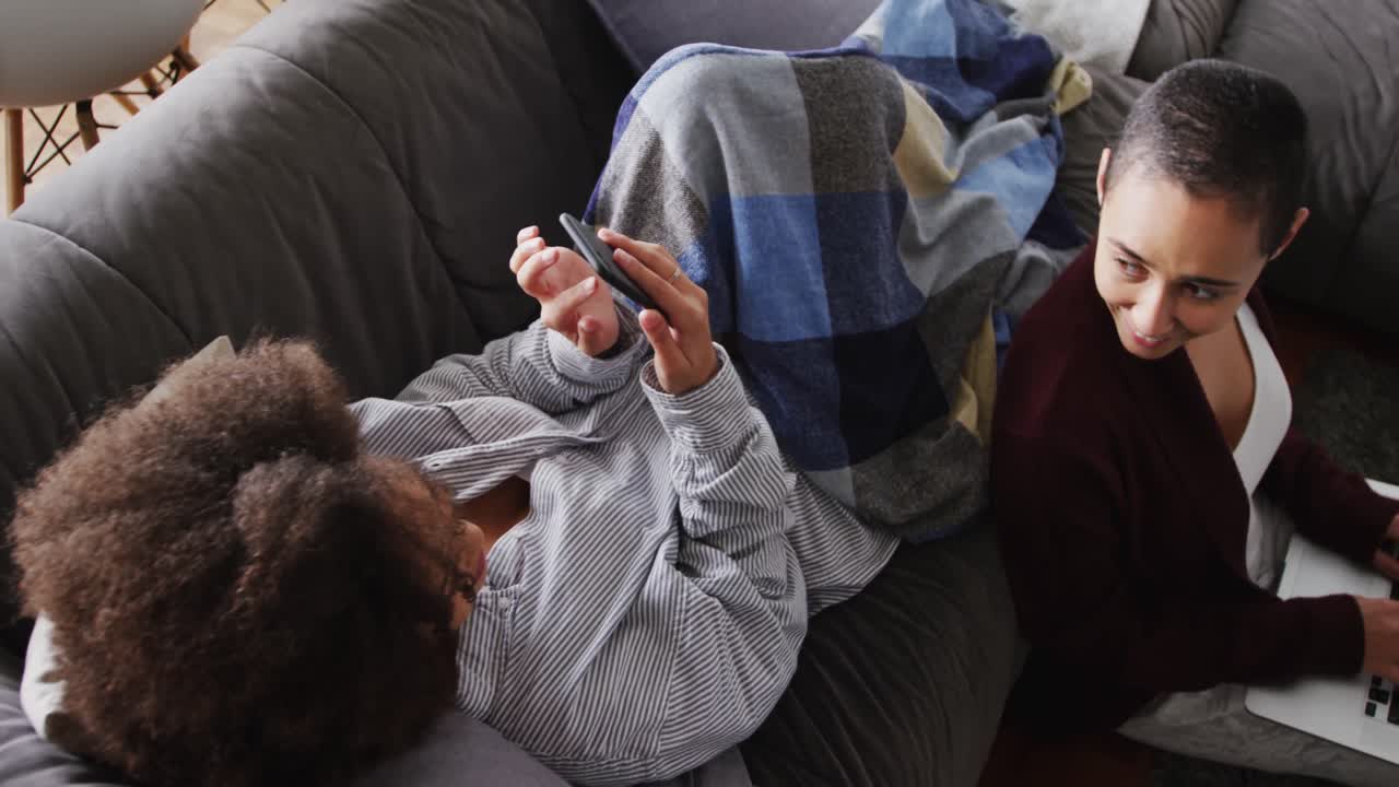Lesbian couple using laptop and mobile phone in living room