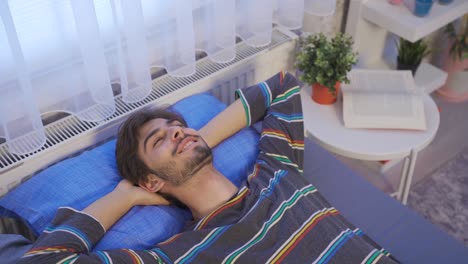 un joven tendido en la cama soñando despierto.