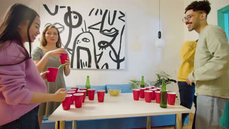 multiethnic young friends playing beer pong at home