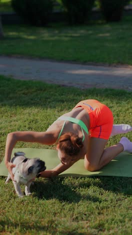 woman and her dog doing yoga in a park