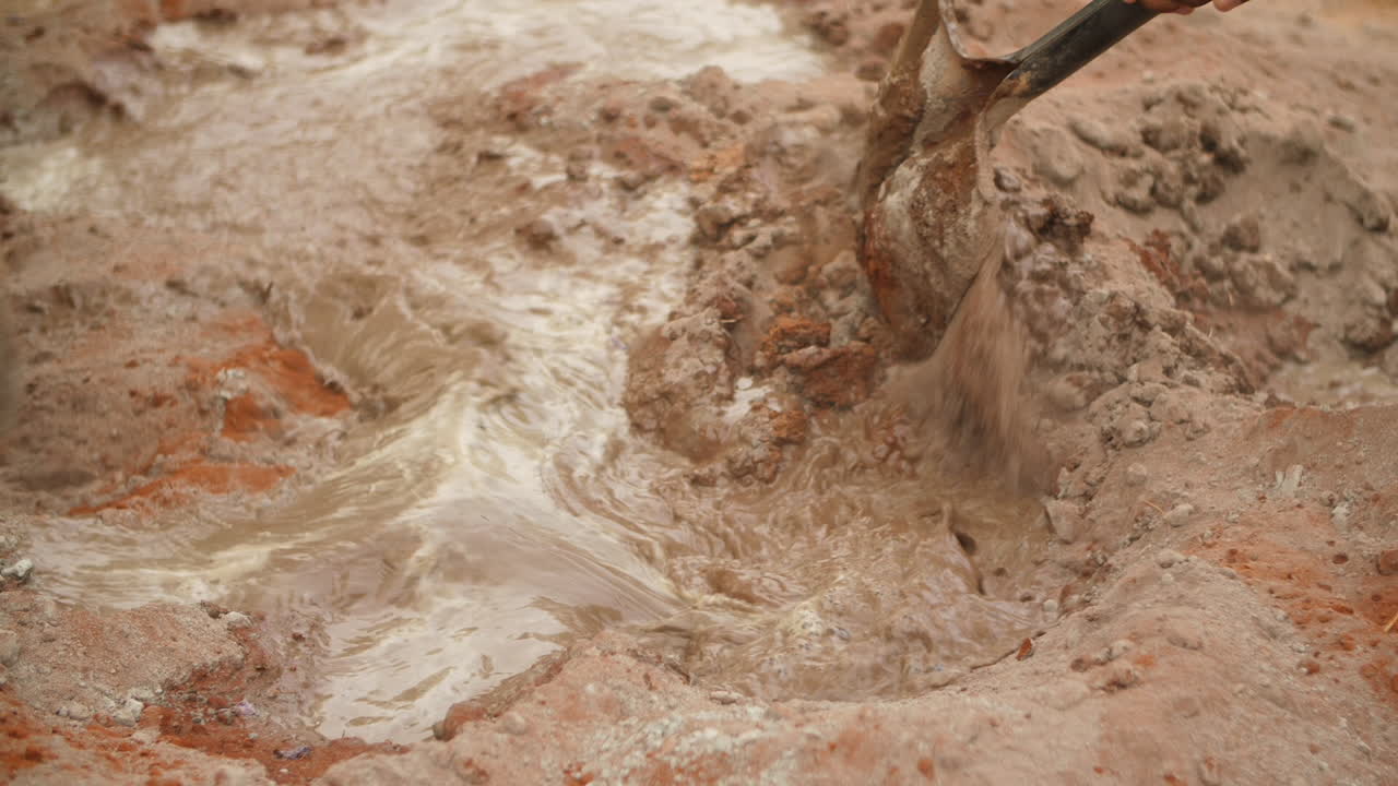 cierre de espadas que mezclan cemento - tierra con agua en el sitio de construcción