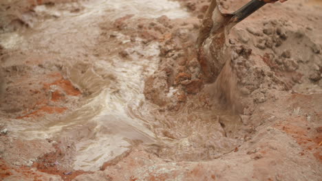 close up of spades mixing cement - soil with water on construction site