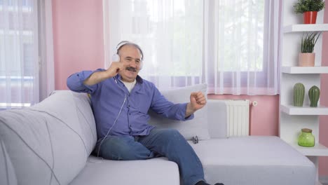 Od-man-looking-out-the-window-and-listening-to-music-with-headphones.