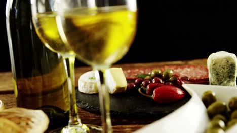 two glasses of wine and a tray with berry fruits and olives