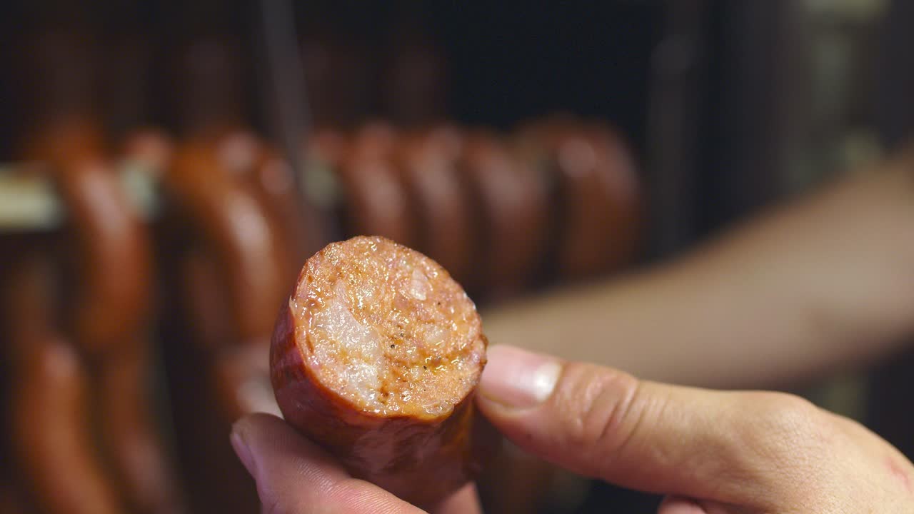 carnicero muestra la composición de la salchicha ahumada