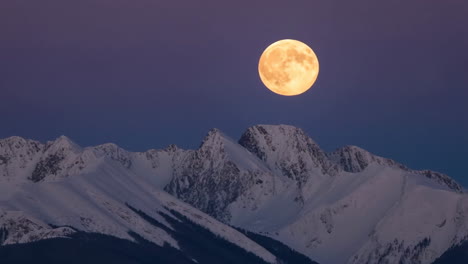 full moon over snow-capped mountains at twilight