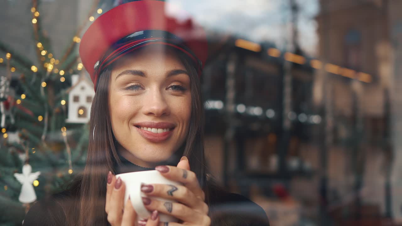 Woman in red hat drinking coffee by the window