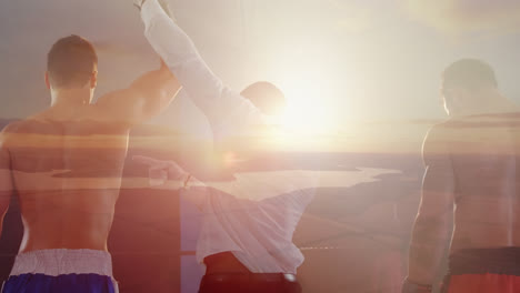 Composite-of-two-boxers-and-referee-raising-arm-of-victor,-with-sunset-over-lake-and-countryside