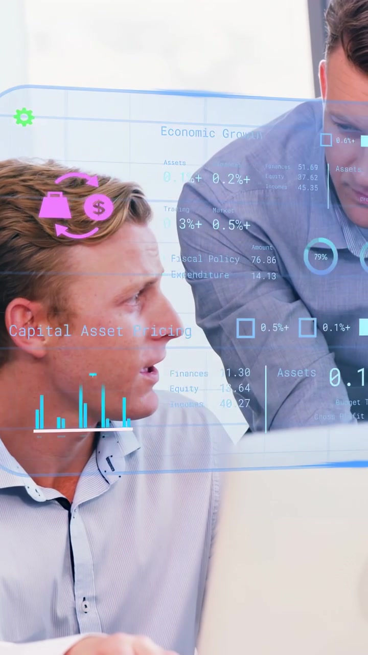 Vertical video: Standing peer leaning in, causing finance charts on laptop, guiding seated man