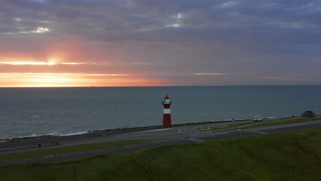 the lighthouse of westkapelle during a bright orange sunset, with a lot of wind