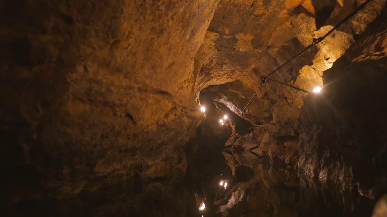 A cinematic zoom in reveals the illuminated walls of the subterranean Labouiche underground river in France