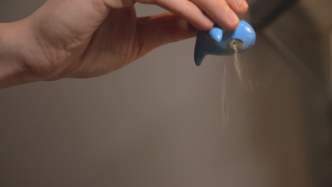 Black Pepper Is Poured From The Shaker To Season Food.- close up shot