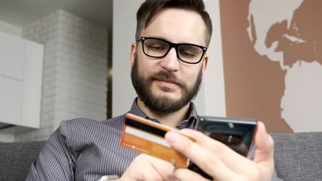 man paying online by bank card at smartphone