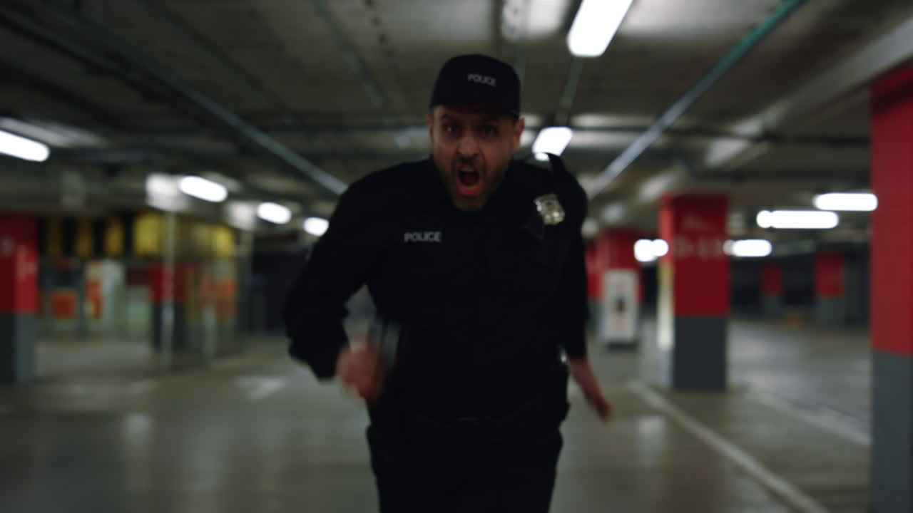 Courageous policeman running on parking. Male cop aiming gun
