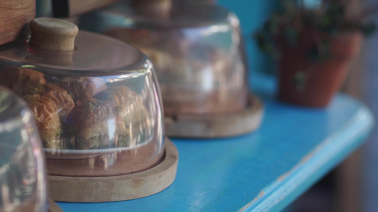 Baklava Pastries Displayed Under Glass Domes on a Blue Counter