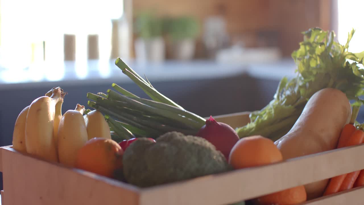 caja de verduras orgánicas en la encimera en una cocina soleada, cámara lenta