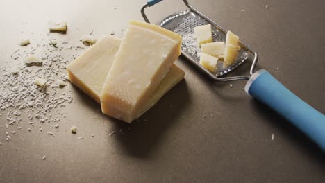 video of block of parmesan cheese and cheese grater cheese on wooden table