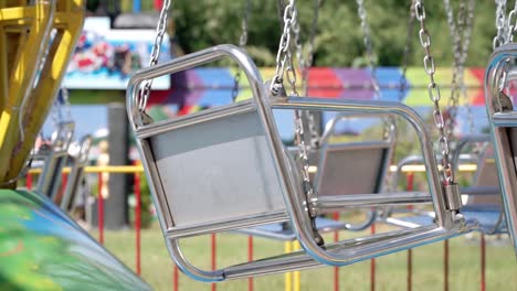 closeup of carousel seat on playground, colorful train passing in background