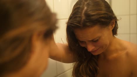 a woman with bruises and scars in her face from being punched and hit looks herself in the mirror