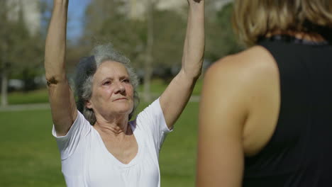 Focused-senior-woman-doing-exercises-with-coach.