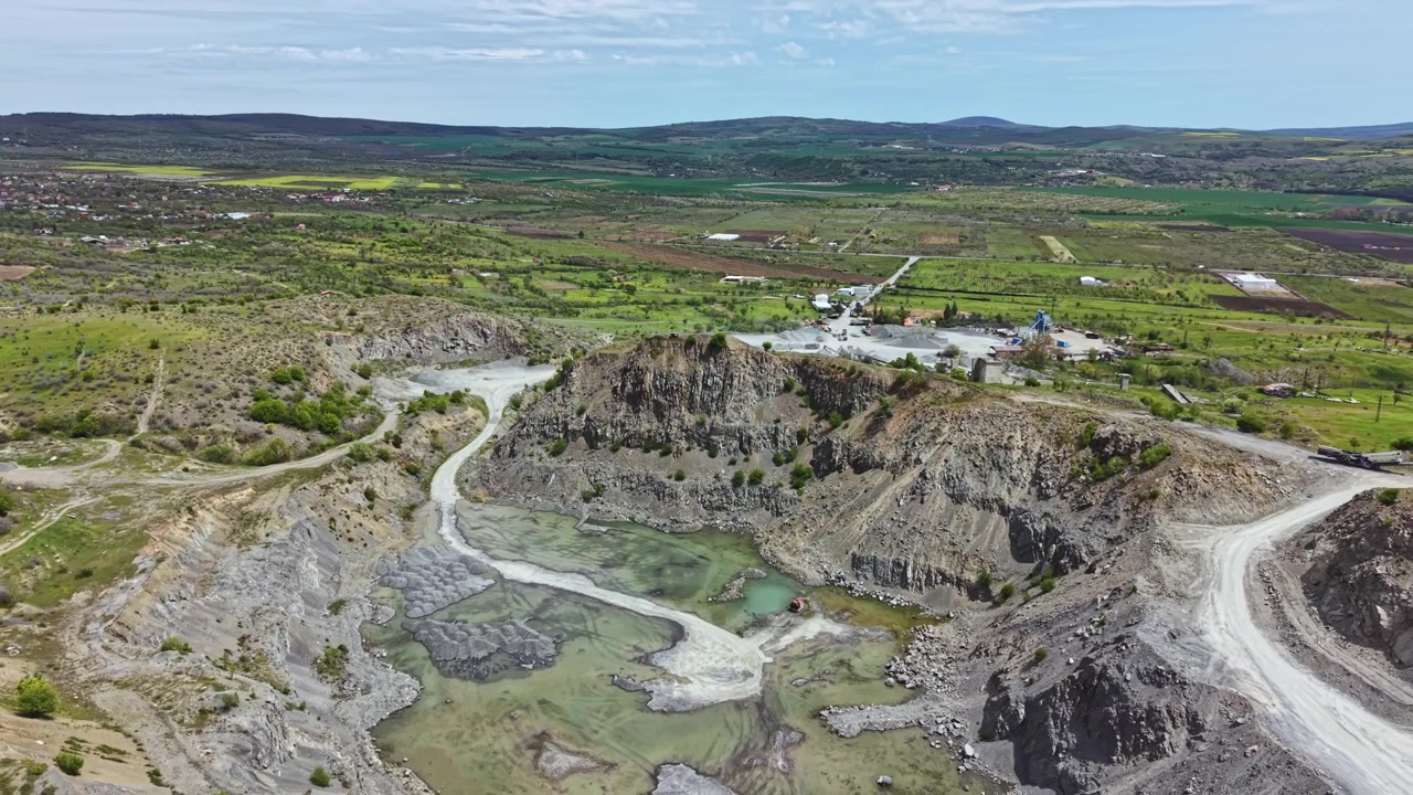 Luftfoto af et stort åbent stenbrud med industriområde.