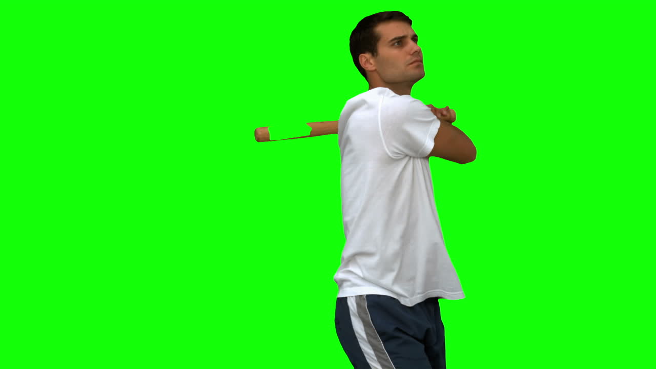 Handsome man playing baseball on green screen