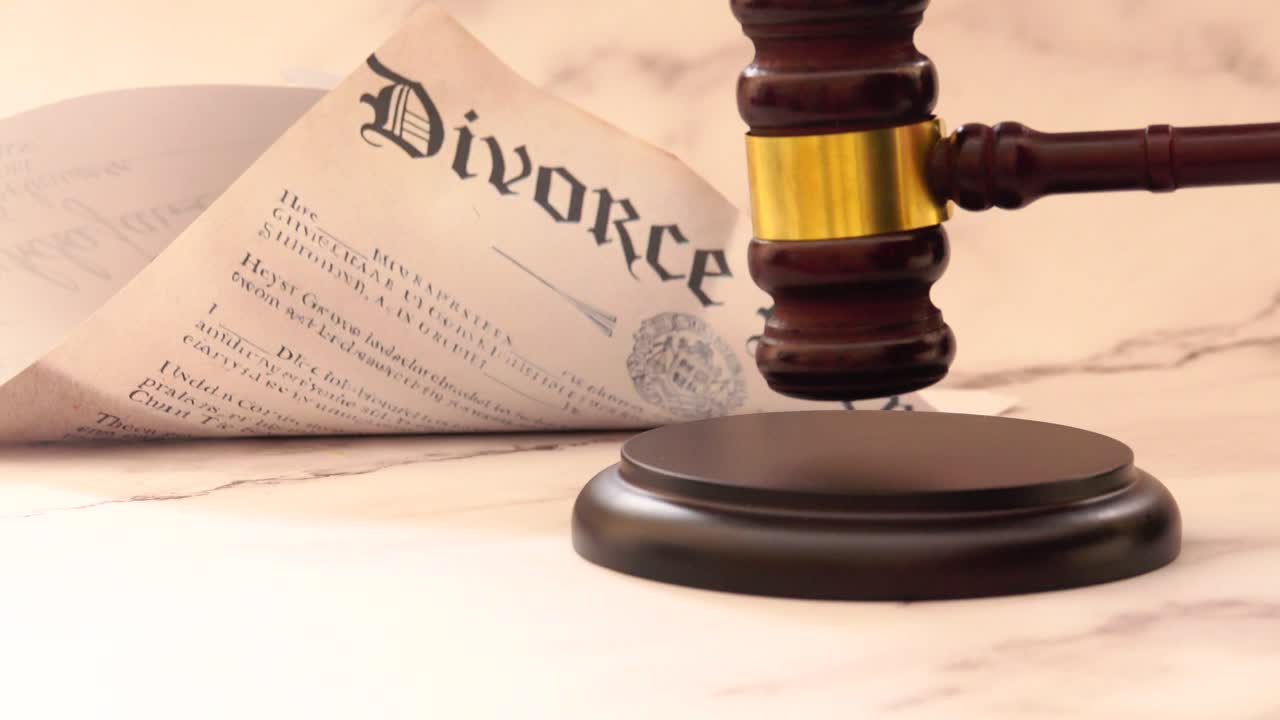 Un decreto di divorzio definitivo è posto accanto a un martelletto di legno da giudice e al suo blocco, a simboleggiare la conclusione legale del matrimonio attraverso il sistema giudiziario familiare