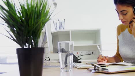 executive with headsets writing in diary at desk in office 4k