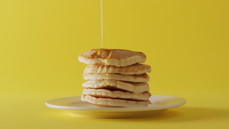 Video-of-maple-syrup-pouring-into-pancakes-on-yellow-background