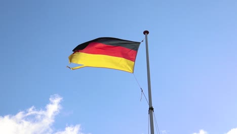 wind blowing the german flag with moving clouds and blue sky in the background