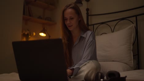 woman working on laptop in bed at night