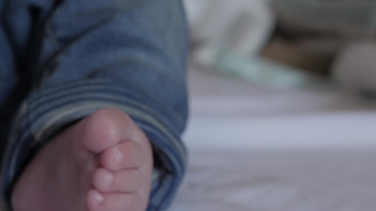 primer plano de los pies del bebé mientras mueve las piernas y los dedos de los pies