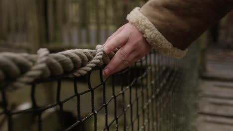 manos tocando el puente de cuerda en la casa del árbol