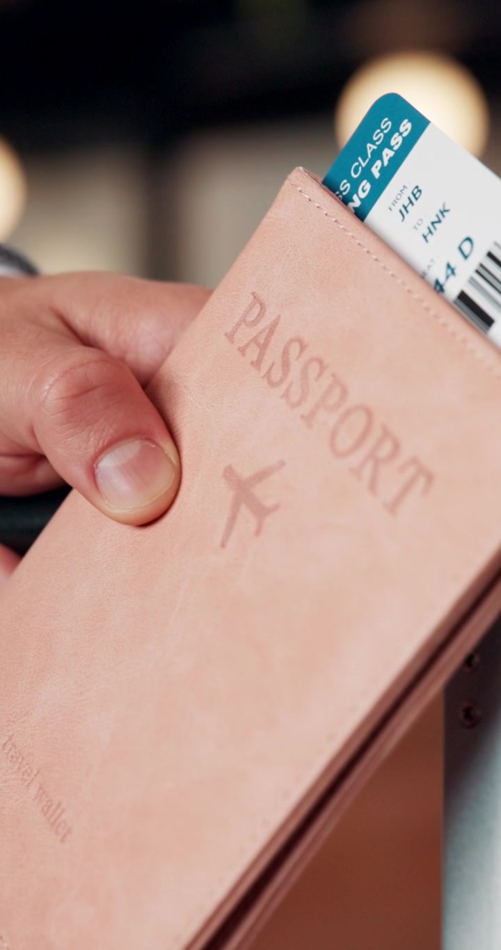 Hand Holding a Passport and Boarding Pass at an Airport