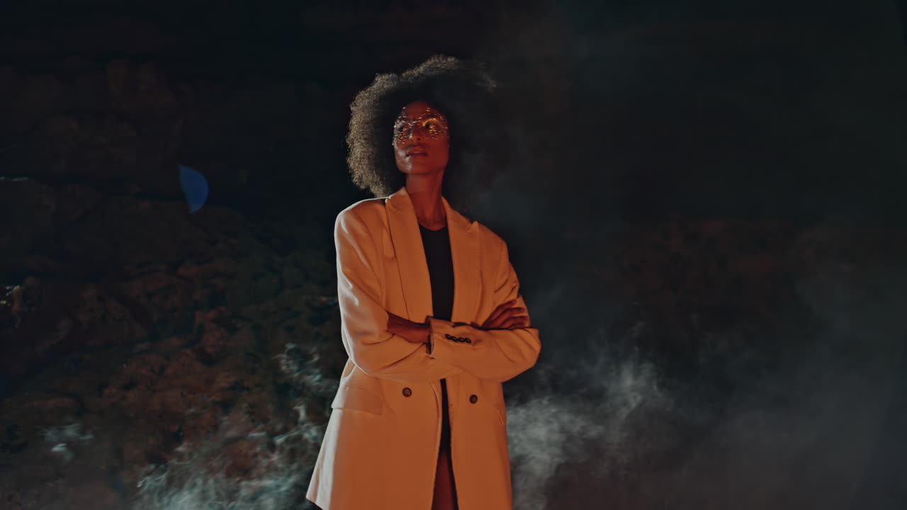 Glamorous woman modeling smoke with shiny makeup. Sexy black hair lady looking