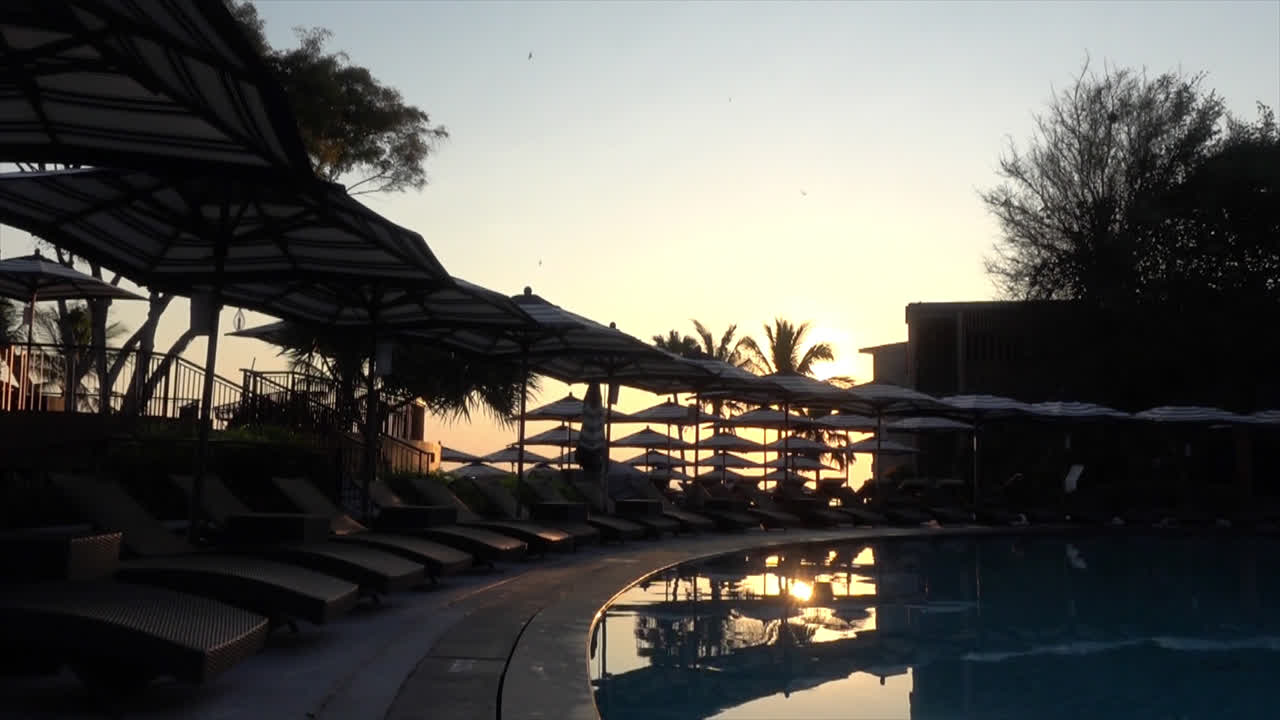 piscina de cama con sombrilla alrededor de la piscina en el complejo hotelero por concepto de vacaciones
