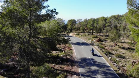 mc pasando por una carretera en la naturaleza en ibiza, filmado con un dron