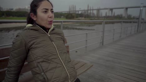 Mujer-Hindú-Concentrada-Haciendo-Sentadillas-Cerca-De-Un-Banco-De-Madera-Al-Aire-Libre