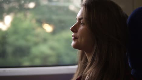 Pensive-woman-relaxing-and-looking-out-of-a-train-window.-Side-view.-Travel,-transport-concept